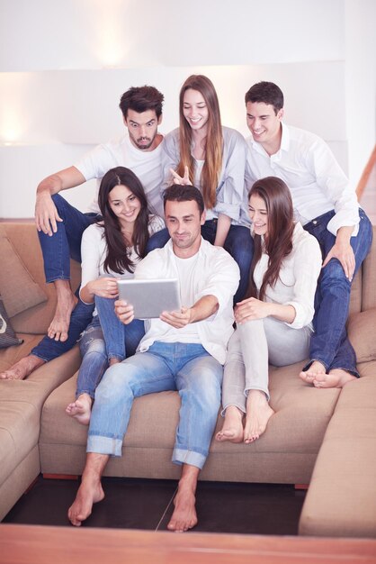 grupo de amigos tomando una foto selfie con una tableta en el interior de una casa moderna