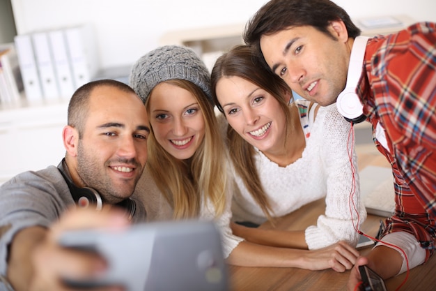 Grupo de amigos tomando fotos de ellos mismos con smartphone