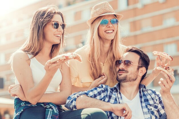 Grupo de amigos tomando sus porciones de pizza