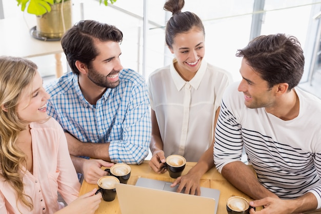 Grupo de amigos usando laptop mientras tomando una taza de café