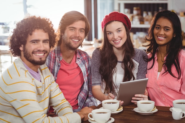 Grupo de amigos usando tableta digital mientras toma una taza de café