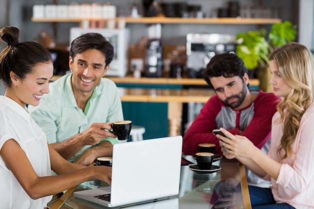 Grupo de amigos usando teléfono móvil y computadora portátil