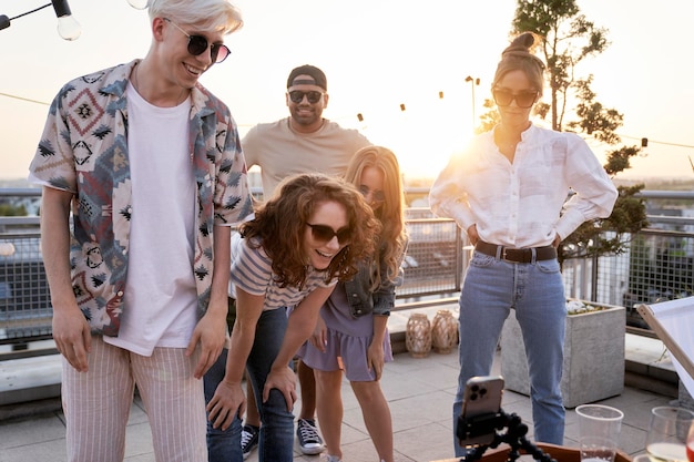 Foto grupo de amigos de varias etnias mirando el teléfono móvil en la fiesta en la azotea