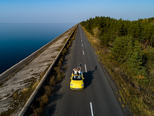 El grupo de amigos viajando en cabriolet amarillo.