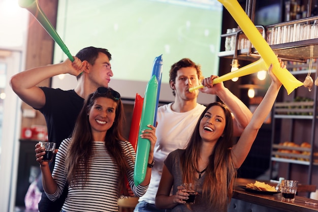 Grupo de amigos viendo el partido de fútbol en el pub