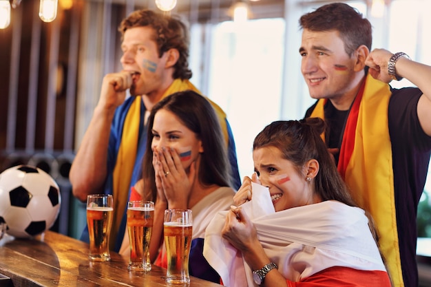 Grupo de amigos viendo el partido de fútbol en el pub