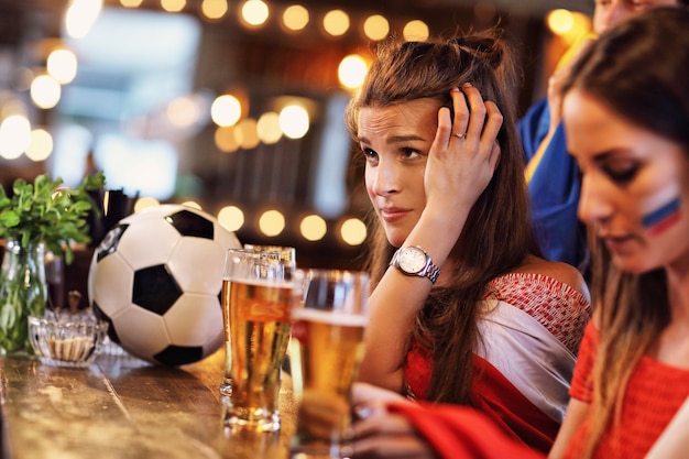 Grupo de amigos viendo el partido de fútbol en el pub