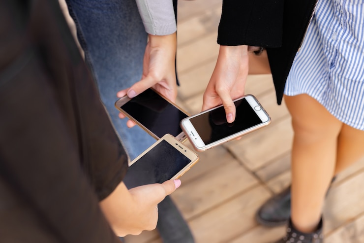 Foto grupo de amigos viendo teléfonos móviles inteligentes. primer plano de las manos