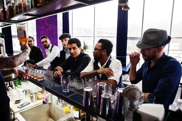 Grupo de apuestos gánsteres retro bien vestidos pasan tiempo en el club Bebiendo whisky en el mostrador del bar Fiesta multiétnica de solteros mafiosos en el restaurante