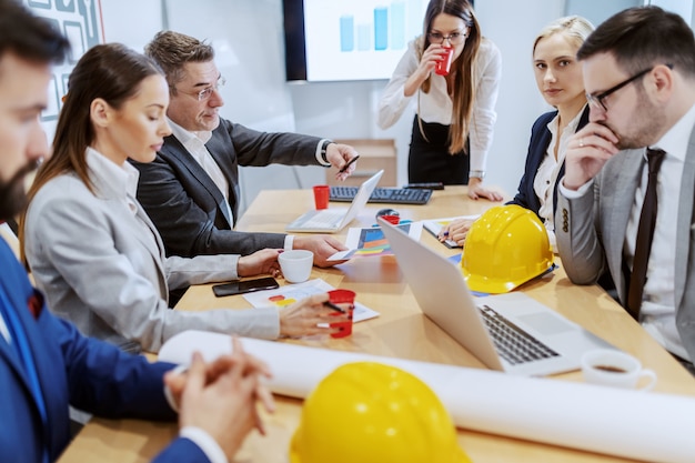 Grupo de arquitecto exitoso sentado en la sala de juntas y discutiendo sobre un nuevo proyecto.