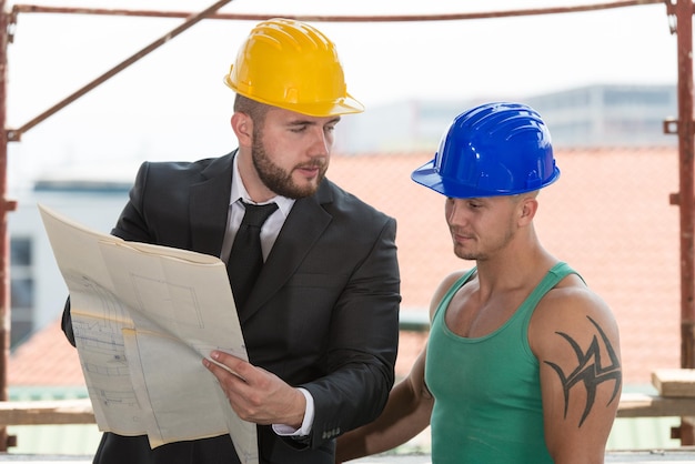 Grupo de arquitecto masculino y trabajador de la construcción en el sitio de construcción