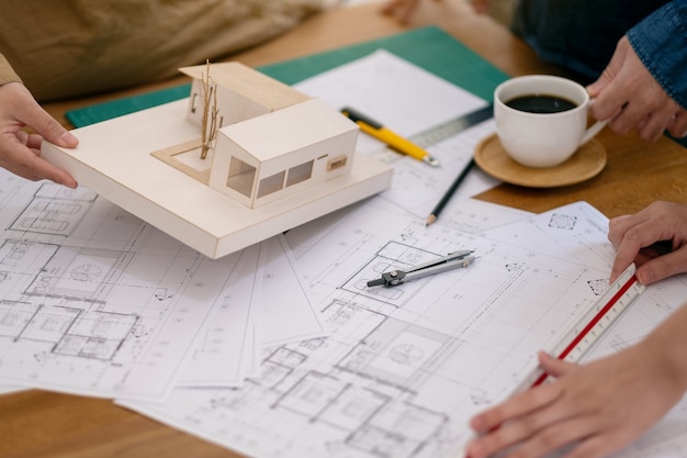 Grupo de un arquitecto trabajando y escala de medición de un modelo de masa en la mesa en la oficina