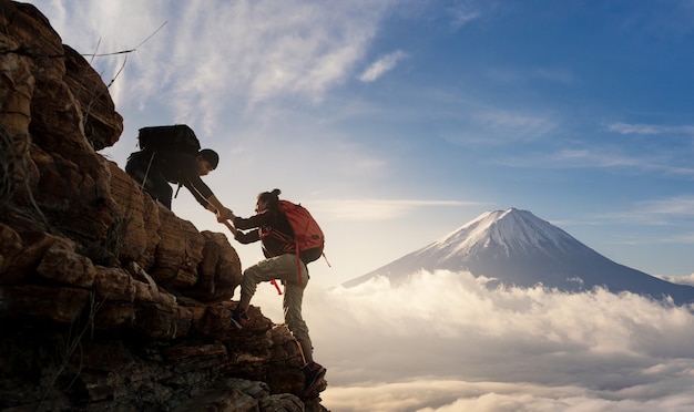 Foto grupo de asia senderismo ayudarse mutuamente silueta en las montañas con la luz solar.