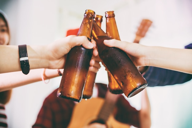 Grupo asiático de amigos de fiesta con bebidas de cerveza alcohólicas y jóvenes disfrutando en un bar a