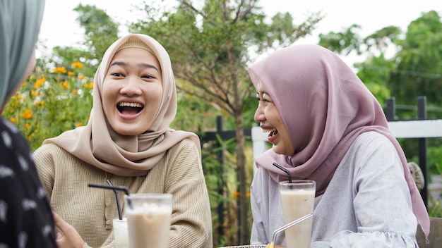 Grupo asiático hijab mujer smilling en café con un amigo