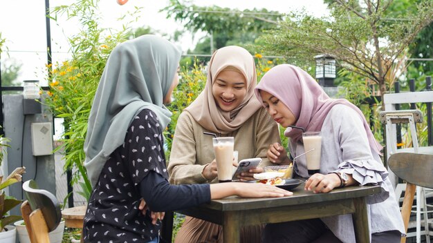 Grupo asiático hijab mujer smilling en café con un amigo