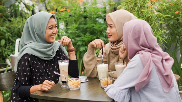 Grupo asiático hijab mujer smilling en café con un amigo