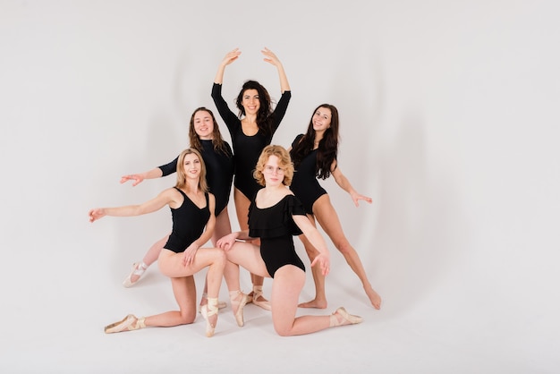 El grupo de bailarines de ballet moderno en traje negro en estudio blanco