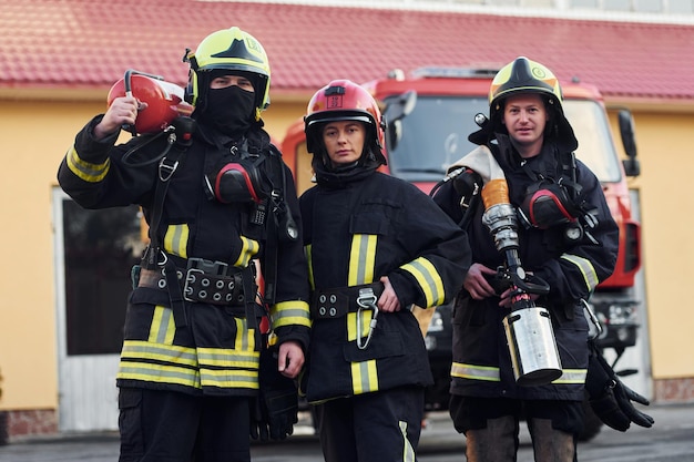 Foto grupo de bomberos con uniforme protector que al aire libre cerca del camión