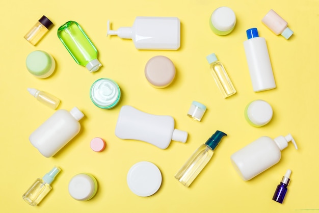 Grupo de botellas de plástico para el cuidado del cuerpo Composición plana con productos cosméticos sobre fondo amarillo espacio vacío para su diseño Conjunto de contenedores de cosméticos blancos vista superior con espacio de copia