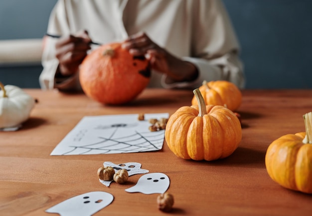 Grupo de calabazas naranjas maduras acostadas en la mesa con fantasmas de papel y dibujo