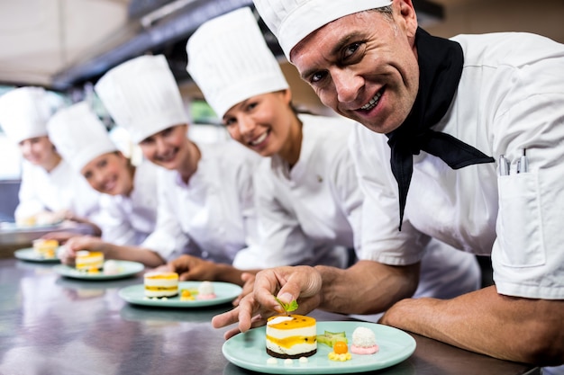 Grupo de chefs decorando deliciosos postres en un plato