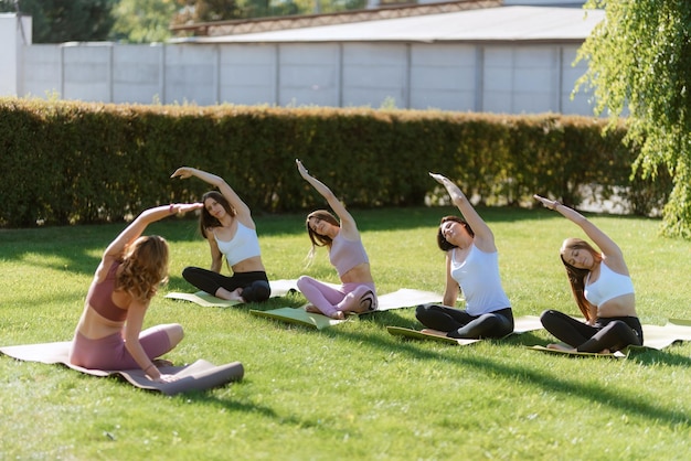 Grupo de chicas jóvenes haciendo yoga al aire libre y cerca del agua