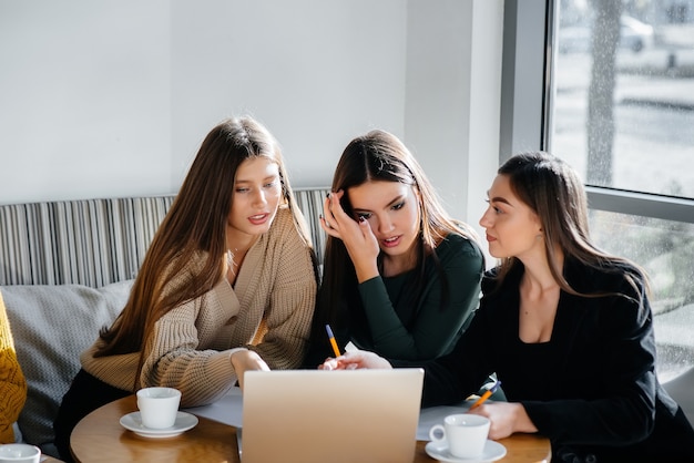 Un grupo de chicas jóvenes se sientan en una oficina y trabajan en computadoras. Comunicación y formación online.