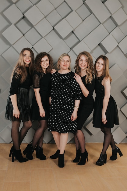 Foto grupo de chicas en vestidos negros en la pared con textura gris