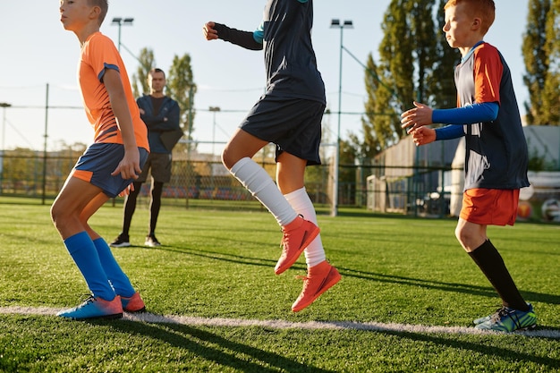 Foto grupo de chicos corriendo en un campo de fútbol verde durante la clase de entrenamiento en la escuela deportiva