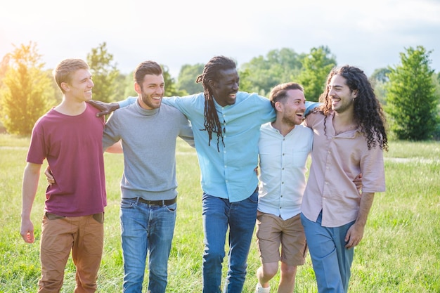 Grupo de chicos de diferentes nacionalidades pasando el rato juntos en el parque disfrutando del buen tiempo