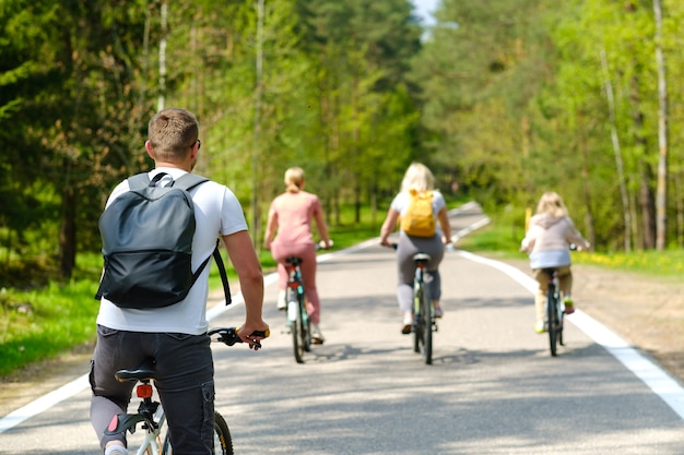 Un grupo de ciclistas con mochilas andan en bicicleta por un camino forestal disfrutando de la naturaleza.