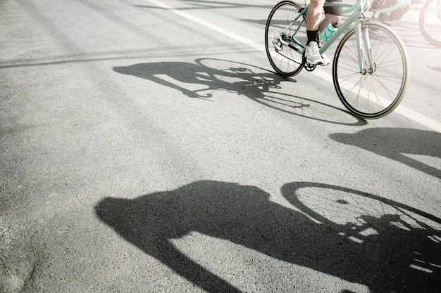 Grupo de ciclistas pedaleando en una bicicleta de carreras con sombra dura en un día soleado.