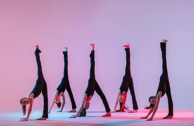 Grupo de cinco adolescentes balrins en trajes ajustados negros están bailando konteporari moderno en al.