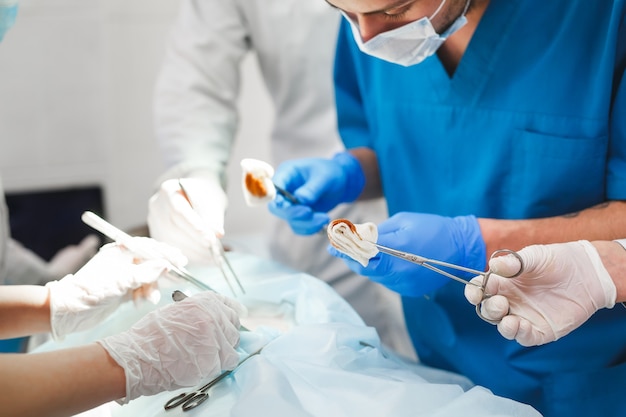 Grupo de cirujanos en el trabajo que operan en quirófano. Equipo de medicina de reanimación con máscaras protectoras con herramientas médicas de acero que salvan al paciente. Cirugía y urgencias.