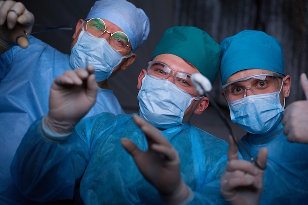 Grupo de cirujanos en el trabajo en quirófano tonificado en azul Equipo médico realizando operación