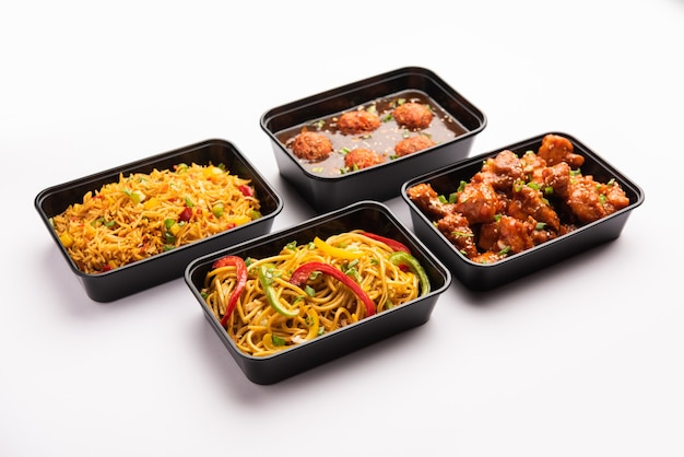 Grupo de comida indochina entregada a domicilio en envases, recipientes o cajas de plástico que contienen fideos schezwan, arroz frito, pollo con chile, manchuria y sopa.