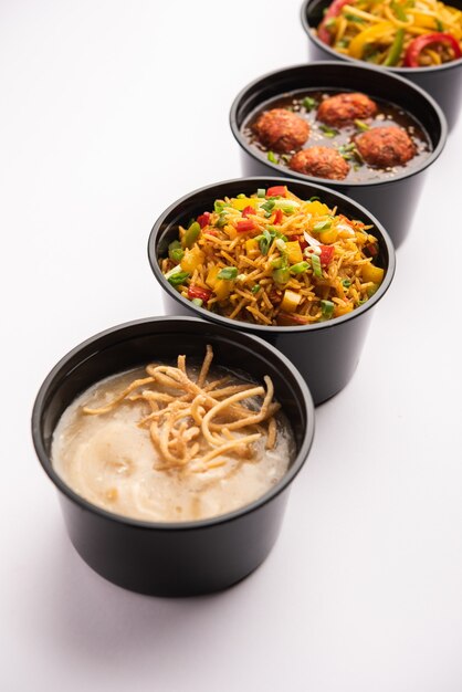 Grupo de comida indochina entregada a domicilio en envases, recipientes o cajas de plástico que contienen fideos schezwan, arroz frito, pollo con chile, manchuria y sopa.