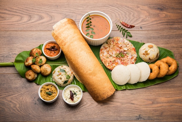 Grupo de comida del sur de la India como Masala Dosa, Uttapam, Idli o sin hacer nada, Wada o vada, sambar, appam, semolina halwa, upma servido sobre hojas de plátano con chutneys coloridos, enfoque selectivo