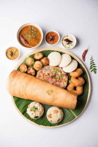 Grupo de comida del sur de la India como Masala Dosa, Uttapam, Idli o sin hacer nada, Wada o vada, sambar, appam, semolina halwa, upma servido sobre hojas de plátano con chutneys coloridos, enfoque selectivo