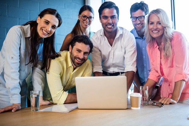 Grupo de compañeros de trabajo mirando una computadora portátil