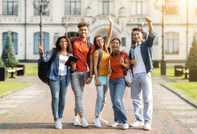 Grupo conceitual de estudantes multiétnicos felizes com pastas de trabalho posando juntos ao ar livre