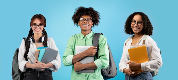 Grupo conceitual inclinado de estudantes multiétnicos posando sobre fundo azul