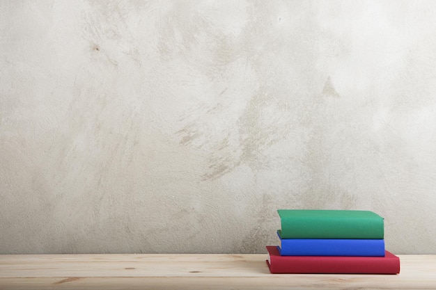 Grupo de concepto de educación y lectura de libros coloridos en la pizarra de pared de hormigón de mesa de madera