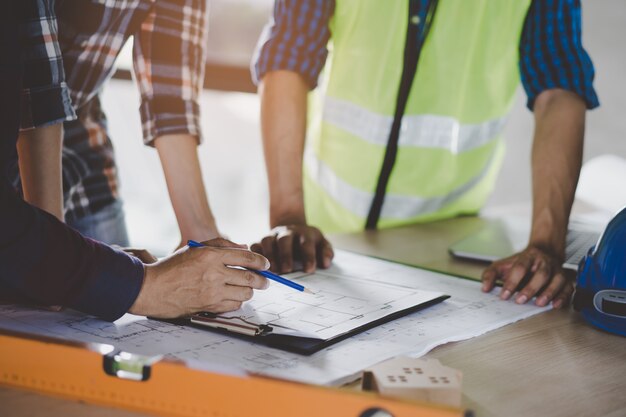 Foto grupo de constructor del equipo que planea y que discute el dibujo casero de la construcción.