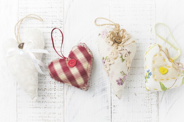 Grupo de corazones festivos de diversos materiales, tela, lana, madera, sobre fondo blanco de madera. Enfoque selectivo. Tarjeta de San Valentín vintage. Vista superior. Lugar para el texto