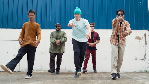 Grupo de coreógrafos de hip hop bailando baile callejero juntos en el esfuerzo de la pared