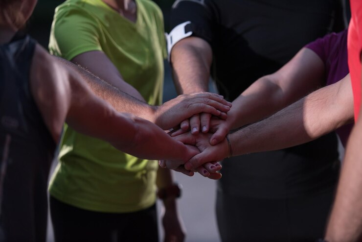 Foto grupo de corredores sanos dándose cinco entre ellos mientras celebran el éxito después de una sesión de entrenamiento.