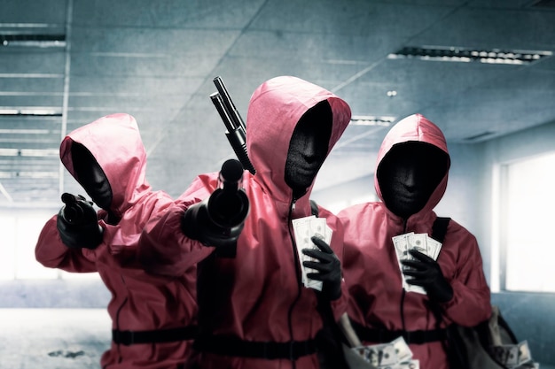 Grupo de criminal en uniforme rosa y una máscara oculta sosteniendo la escopeta después del robo del edificio