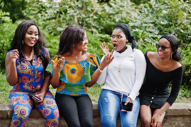 Grupo de cuatro chicas afroamericanas sentadas al aire libre y divirtiéndose